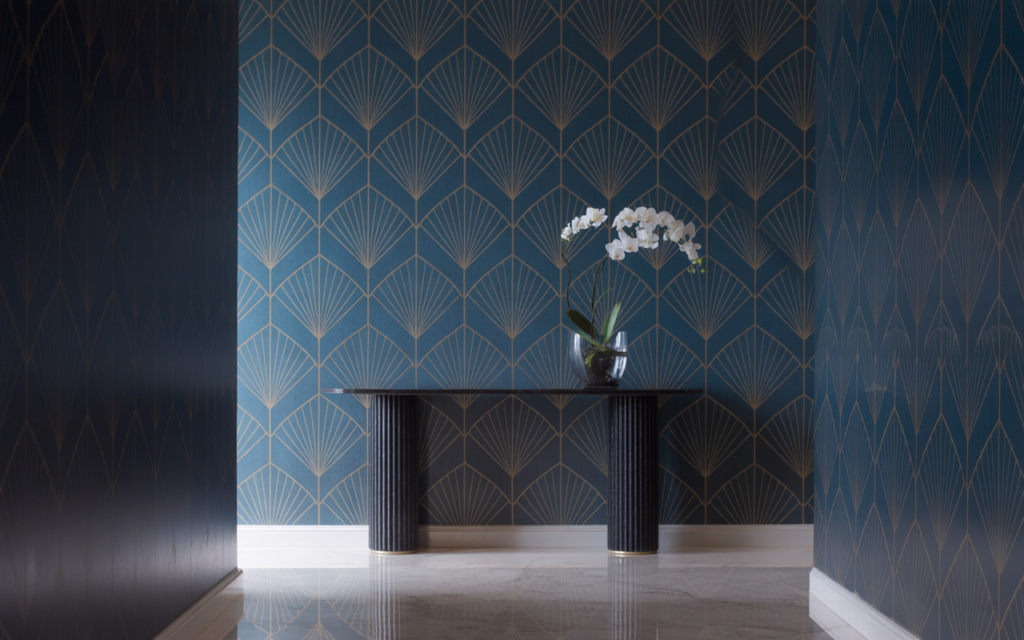 Elegant hallway featuring a geometric Art Deco wallcovering with gold fan patterns on a deep blue wall, complemented by a minimalist black console table.